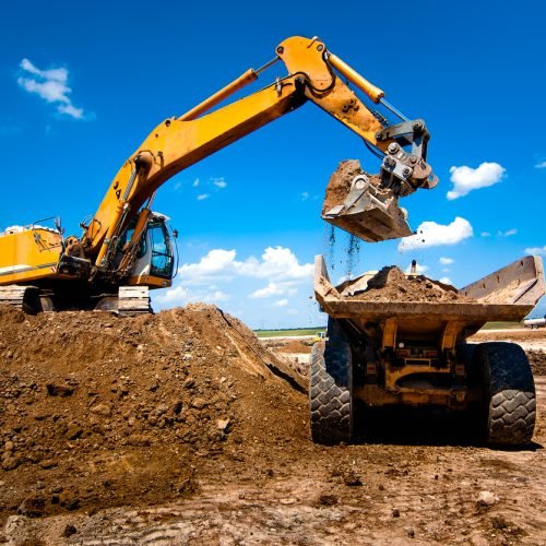 Industrial truck loader excavator moving earth and unloading into a dumper truck